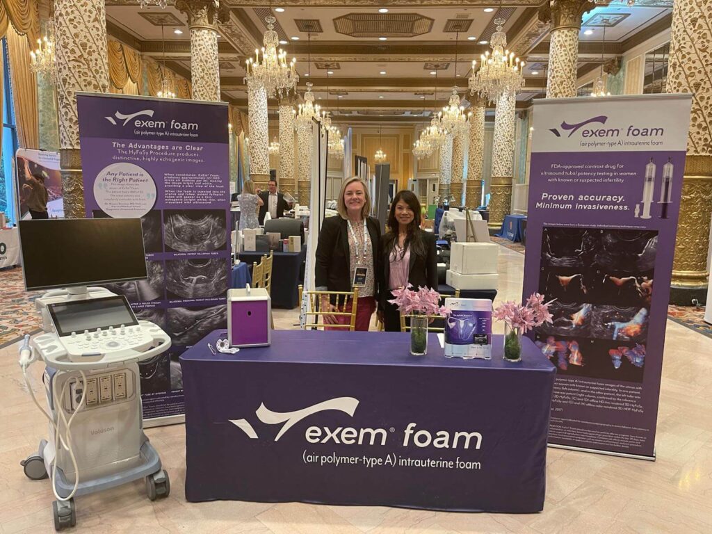 Fantomiq HyFoSy phantom on display at a medical conference, featured at the ExEm Foam booth alongside ultrasound equipment and representatives, demonstrating its application in intrauterine procedures.